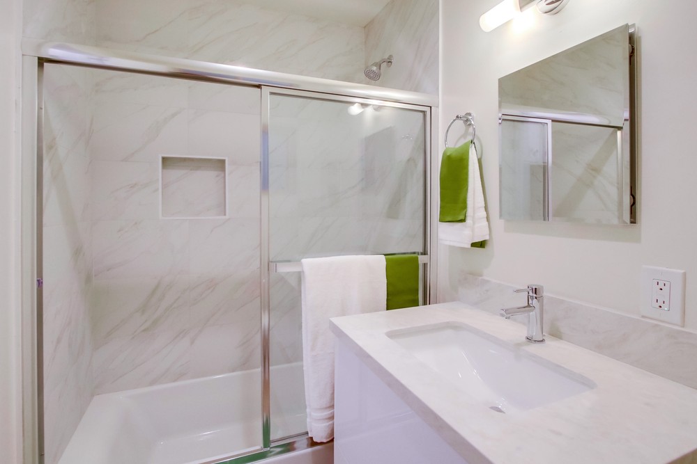 Staged spa-style bathroom with marble-look tile, frameless glass shower and modern vanity